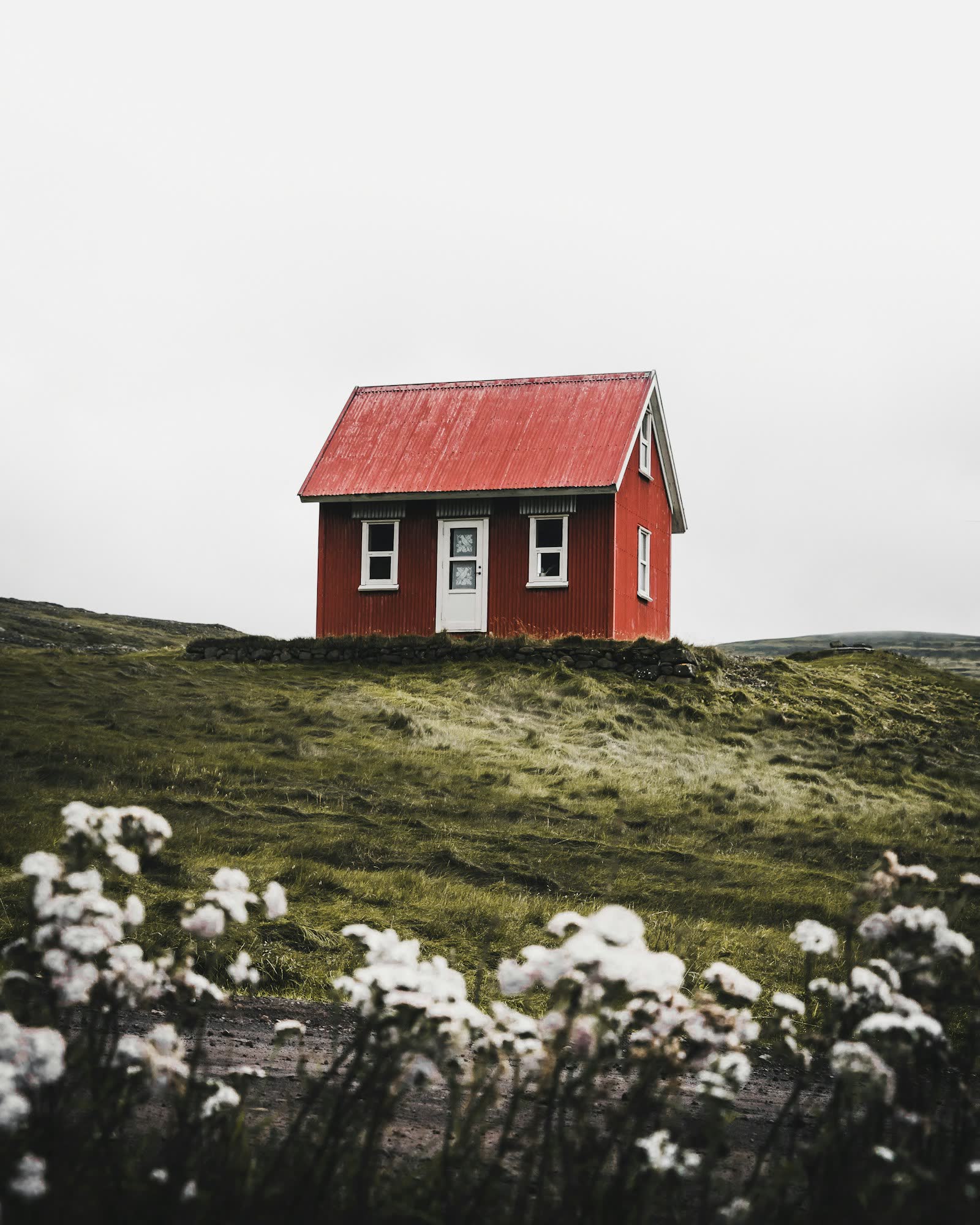 Small traditional cottage with a red roof on an open hillside